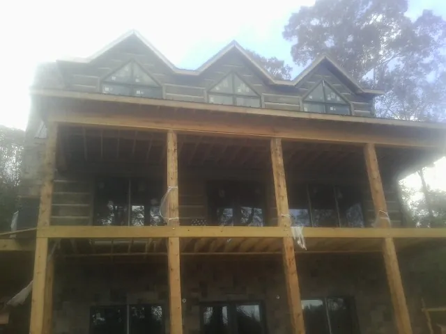 Dormers and porch framing on a large log home under construction — Roof Coating work by our crew in Almo