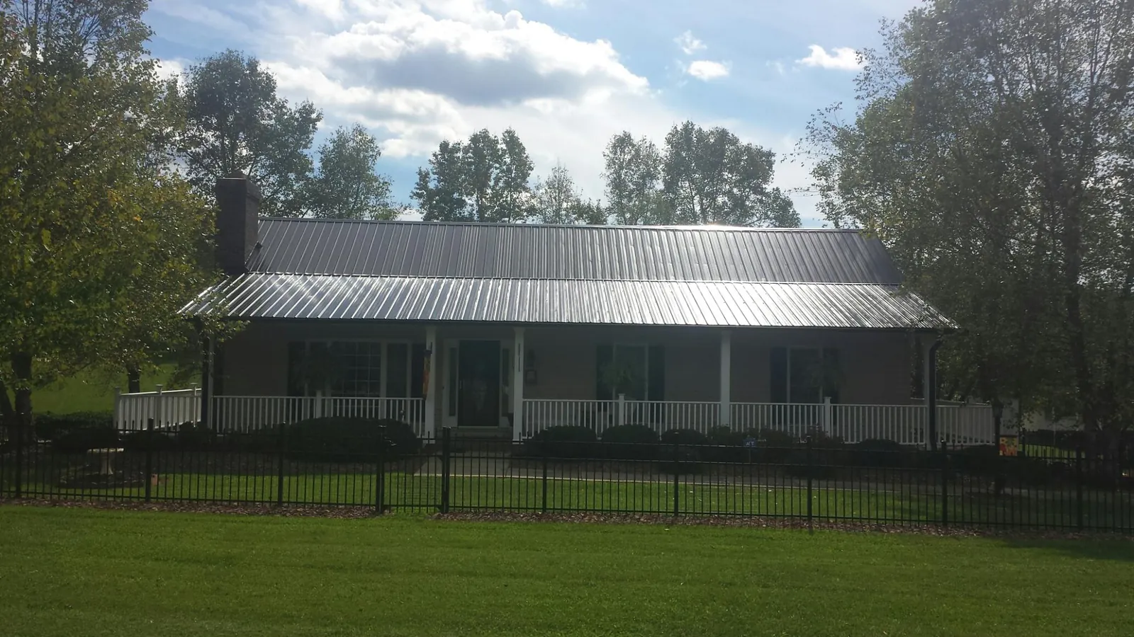 Gray metal roof on a brick ranch with a full width front porch — Gutter Guard Installation work by our crew in Almo