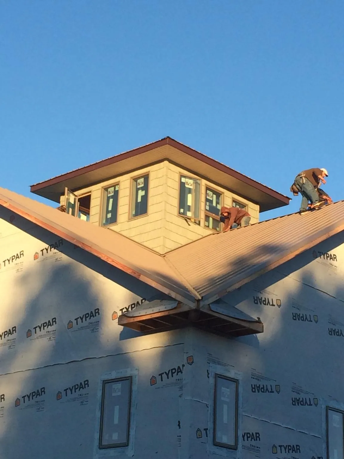 Roofers working around a rooftop cupola on a new metal roof at sunset — Roof Waterproofing in Almo by Roofing Brothers